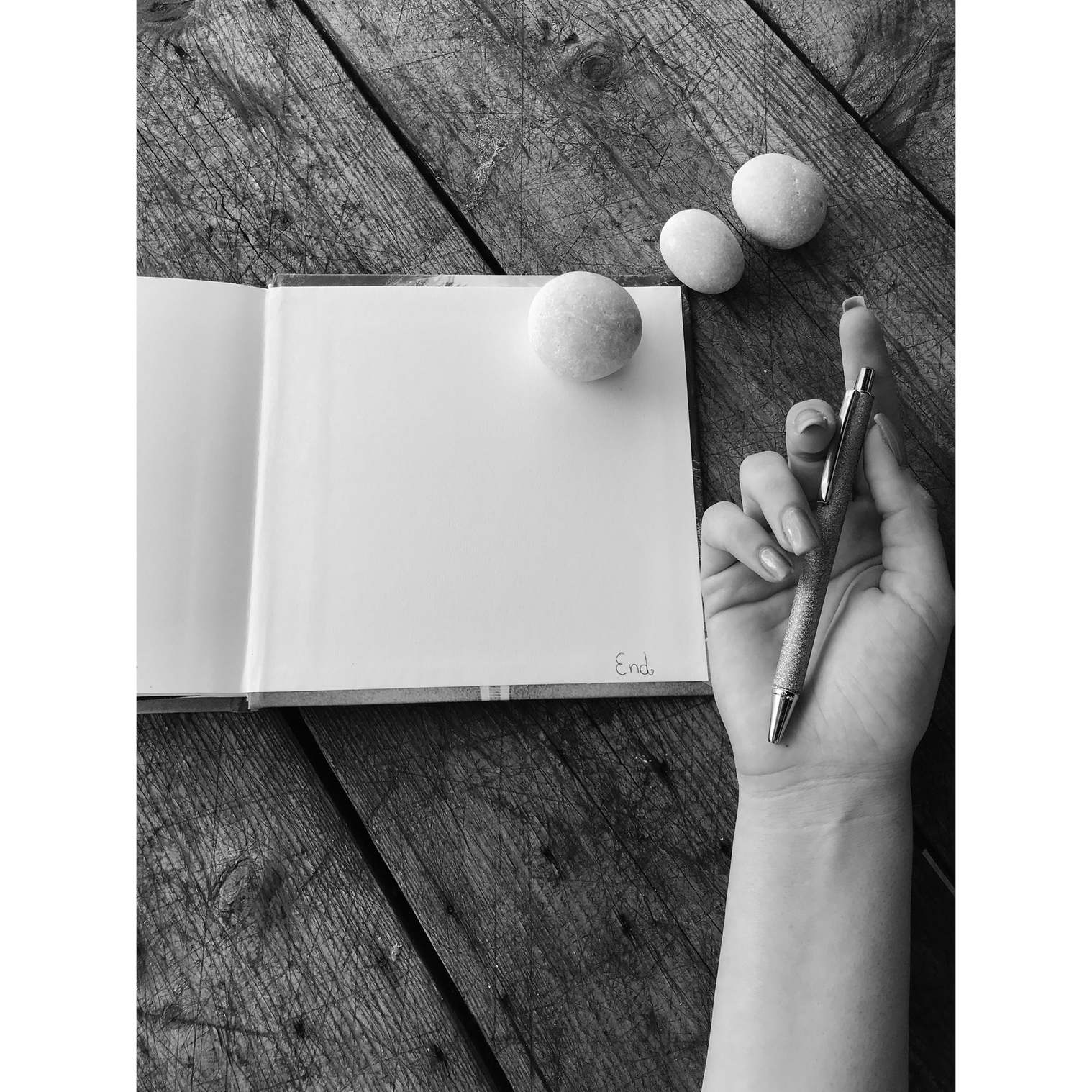 Hand mit Stift über Notizbuch auf Holzoberfläche